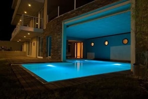 Une maison moderne dotée d’une piscine, d’une façade en pierre et d’un balcon.