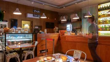 Un café au décor intérieur en bois, un comptoir où sont exposées les boissons, et des tables où l’on sert des plats et des boissons.