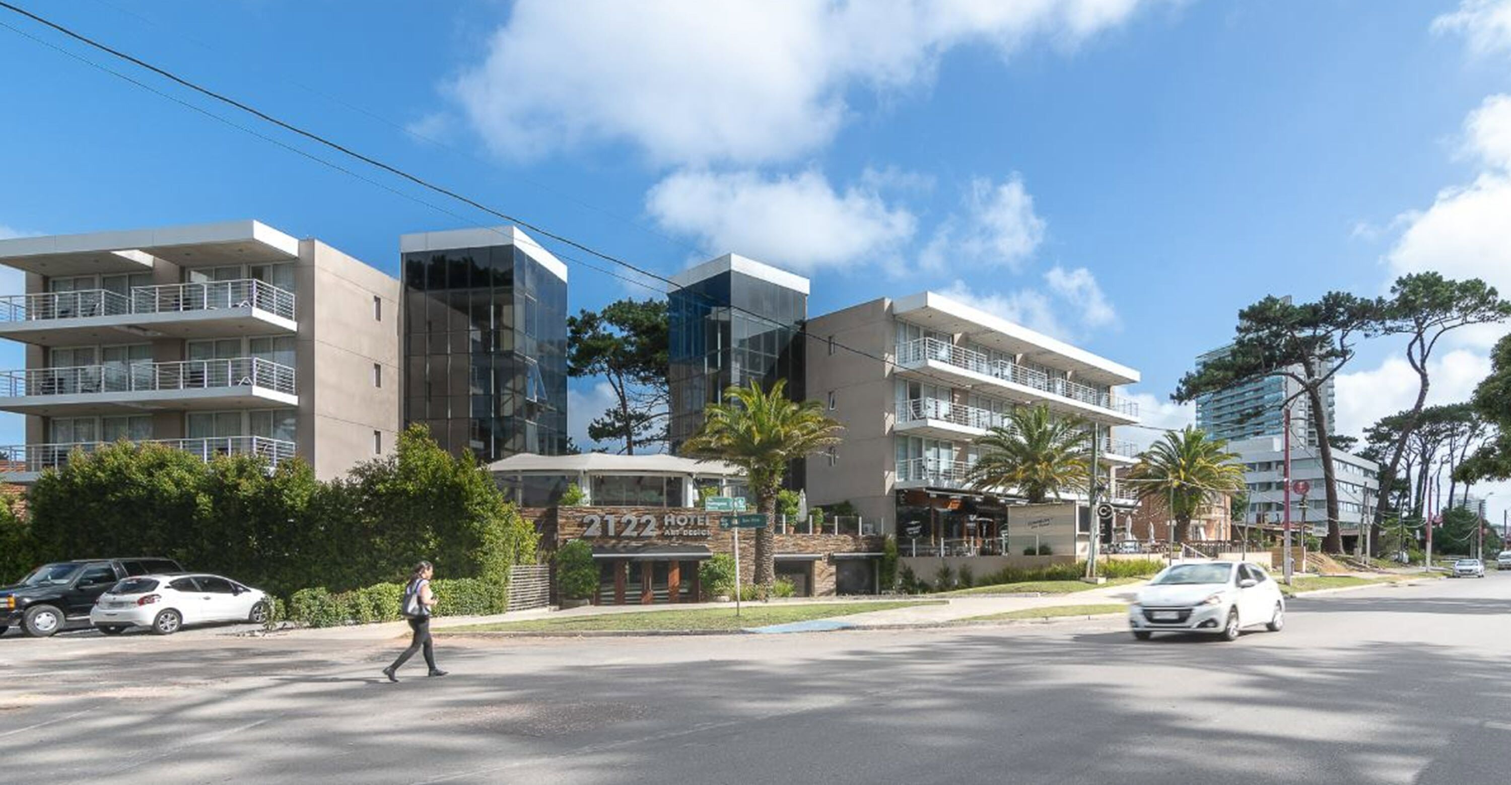 A modern hotel with multiple floors, balconies, and a well-maintained outdoor area with palm trees.