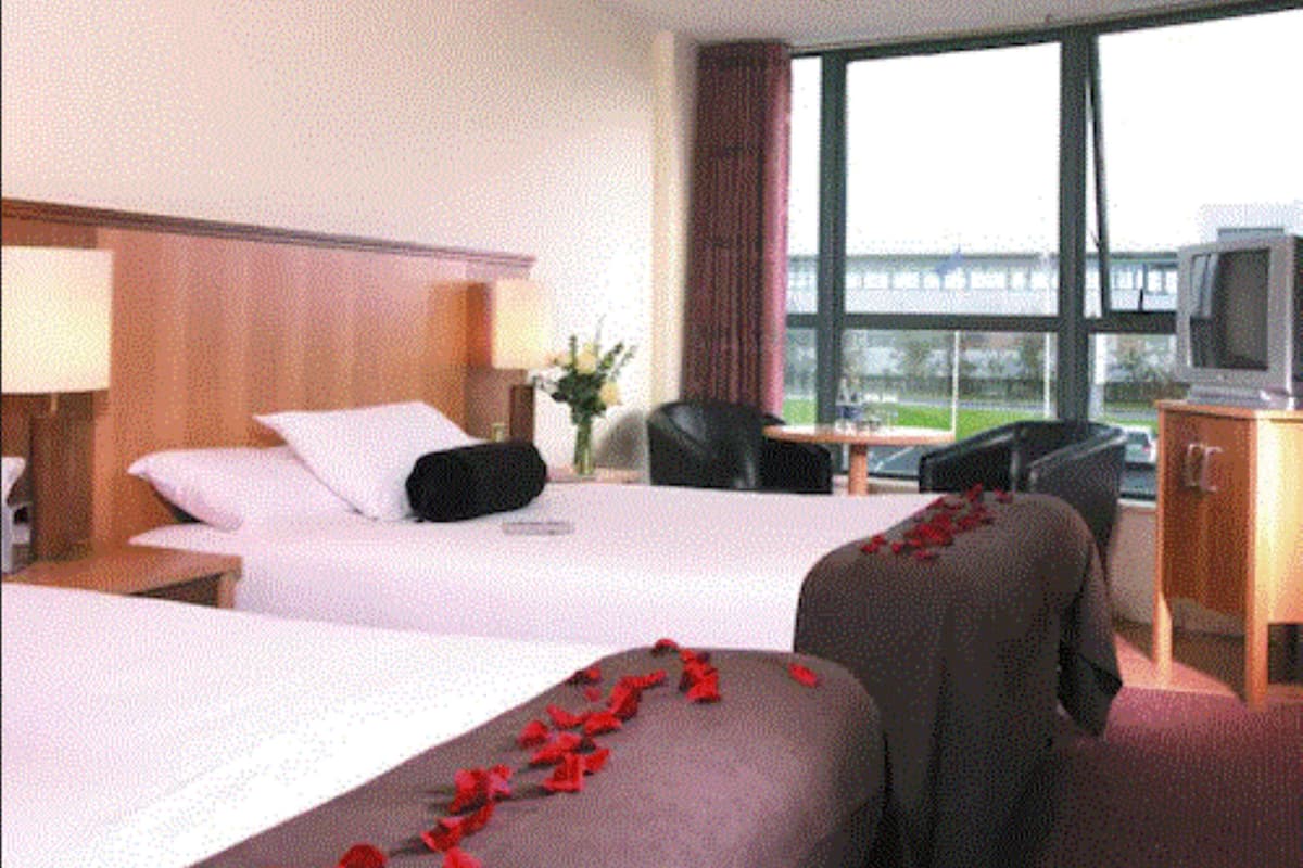 Habitación de hotel con dos camas, un televisor, un escritorio y ventana con vistas.
