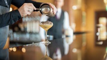 A bartender pouring a drink into a martini glass.