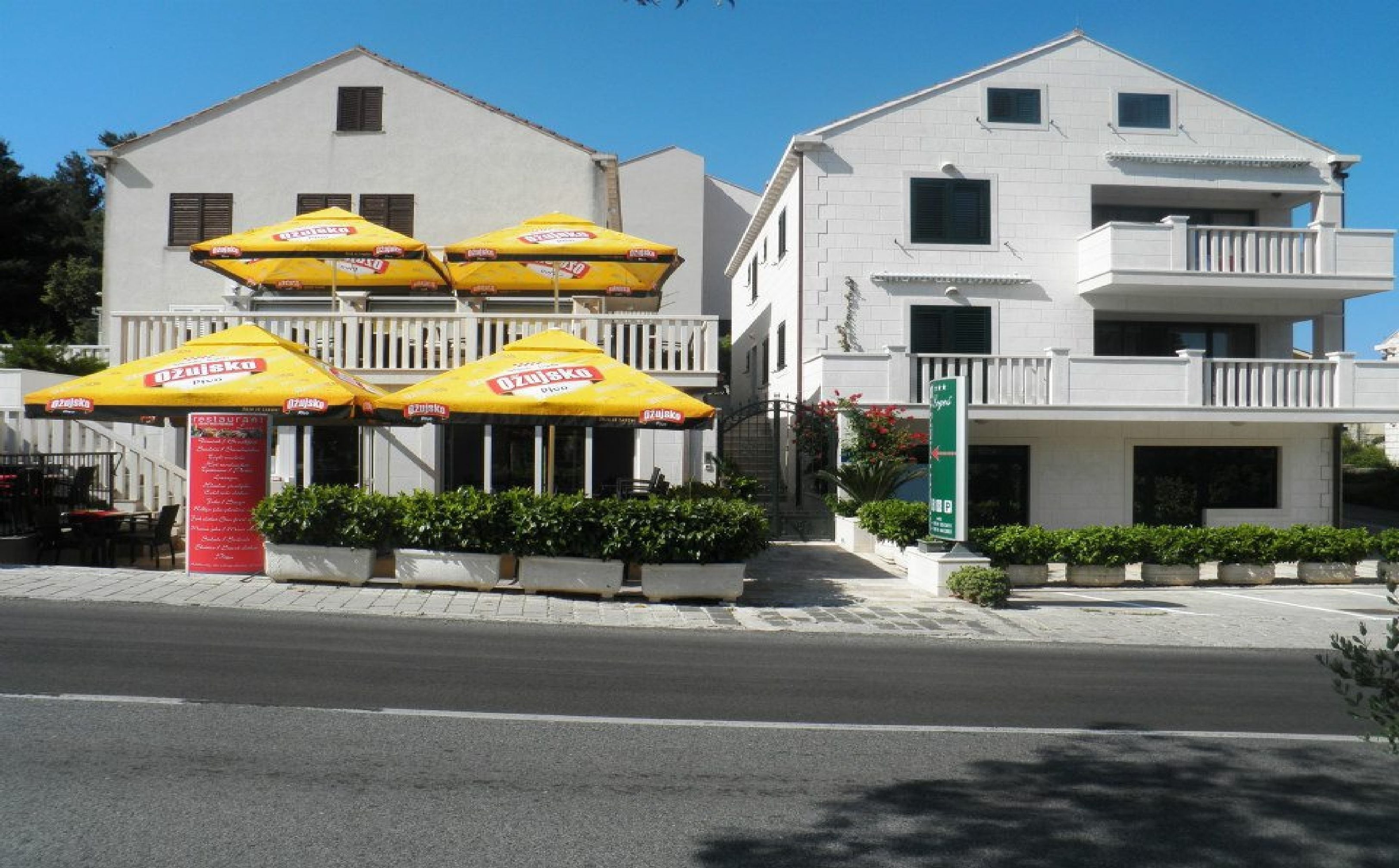A building with outdoor seating and a green sign indicating a parking area.