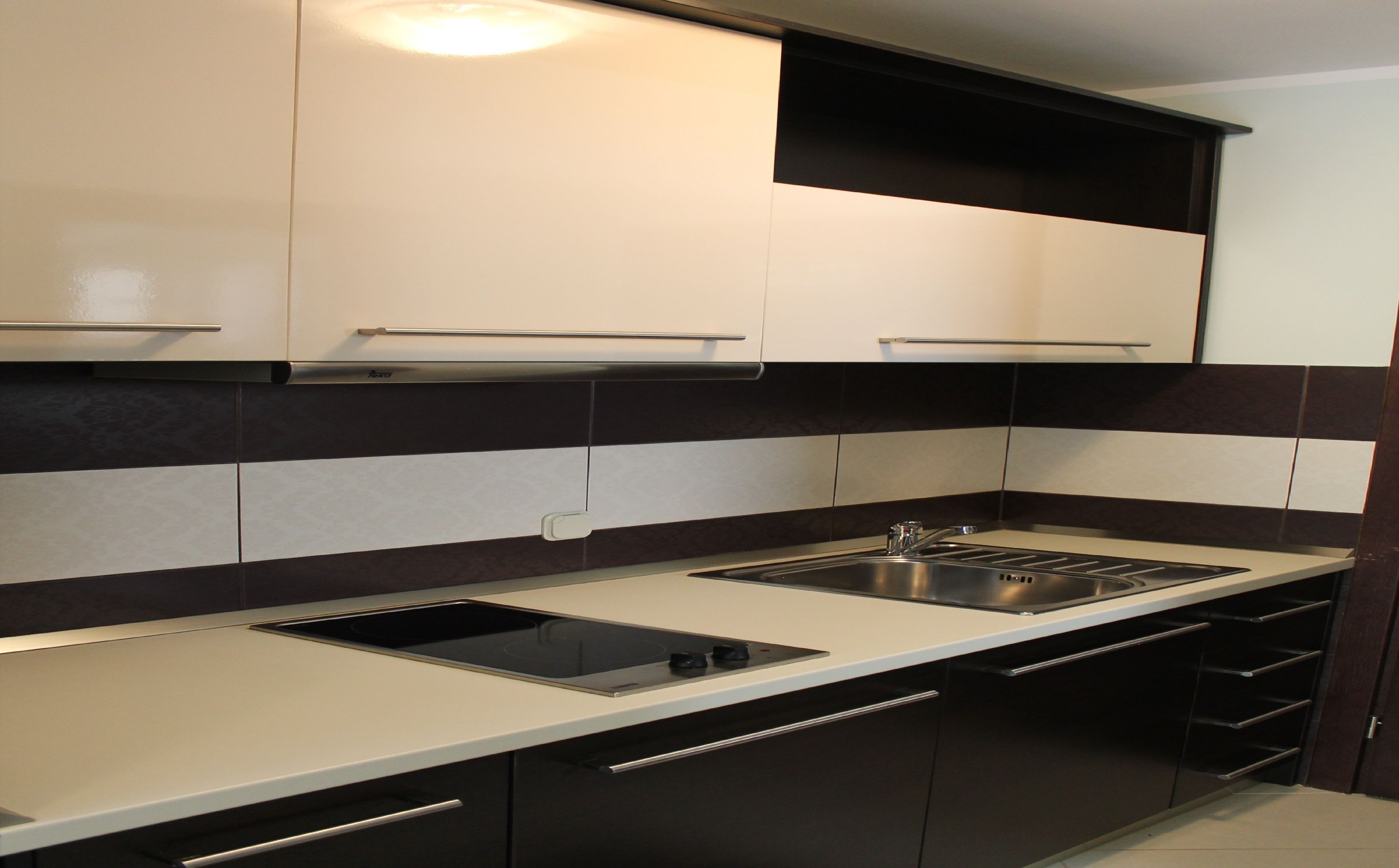 A modern kitchen with a black and white backsplash, stainless steel appliances, and a built-in oven.