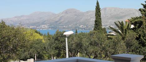 A balcony with a view of a mountainous landscape and a body of water.