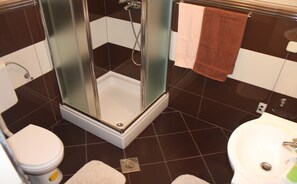 Kylpyhuone, jossa on lasiseinällä varustettu suihku, wc ja pesuallas.
