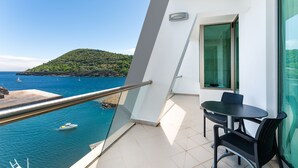 A balcony with a view of the sea, a table, and chairs. - Angra Marina Hotel (Angra do Heroismo)