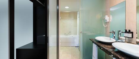 Un baño moderno con cabina de ducha de vidrio, bañera y tocador doble.