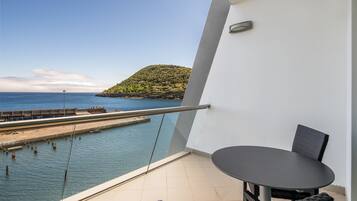 A balcony with a view of the sea and a distant hill.
