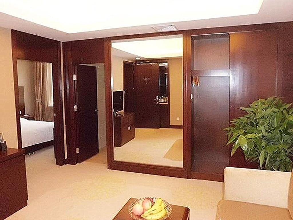 Een hotelkamer met een bed, een bureau, een stoel, een grote spiegel en een kamerplant.
