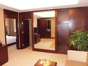 A hotel room with a bed, a desk, a chair, a large mirror, and a potted plant. - Xi'an Kunming Garden Hotel (Seoul South Road Subway Station Branch) (Xi'an)