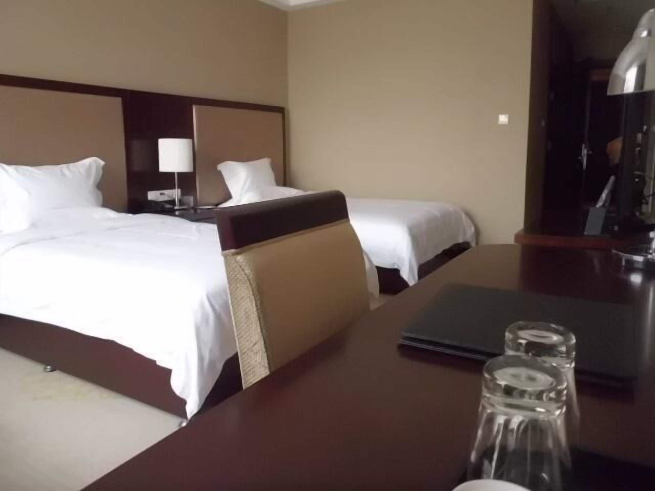 Een hotelkamer met twee bedden, een bureau, een lamp en een koffiezetapparaat.