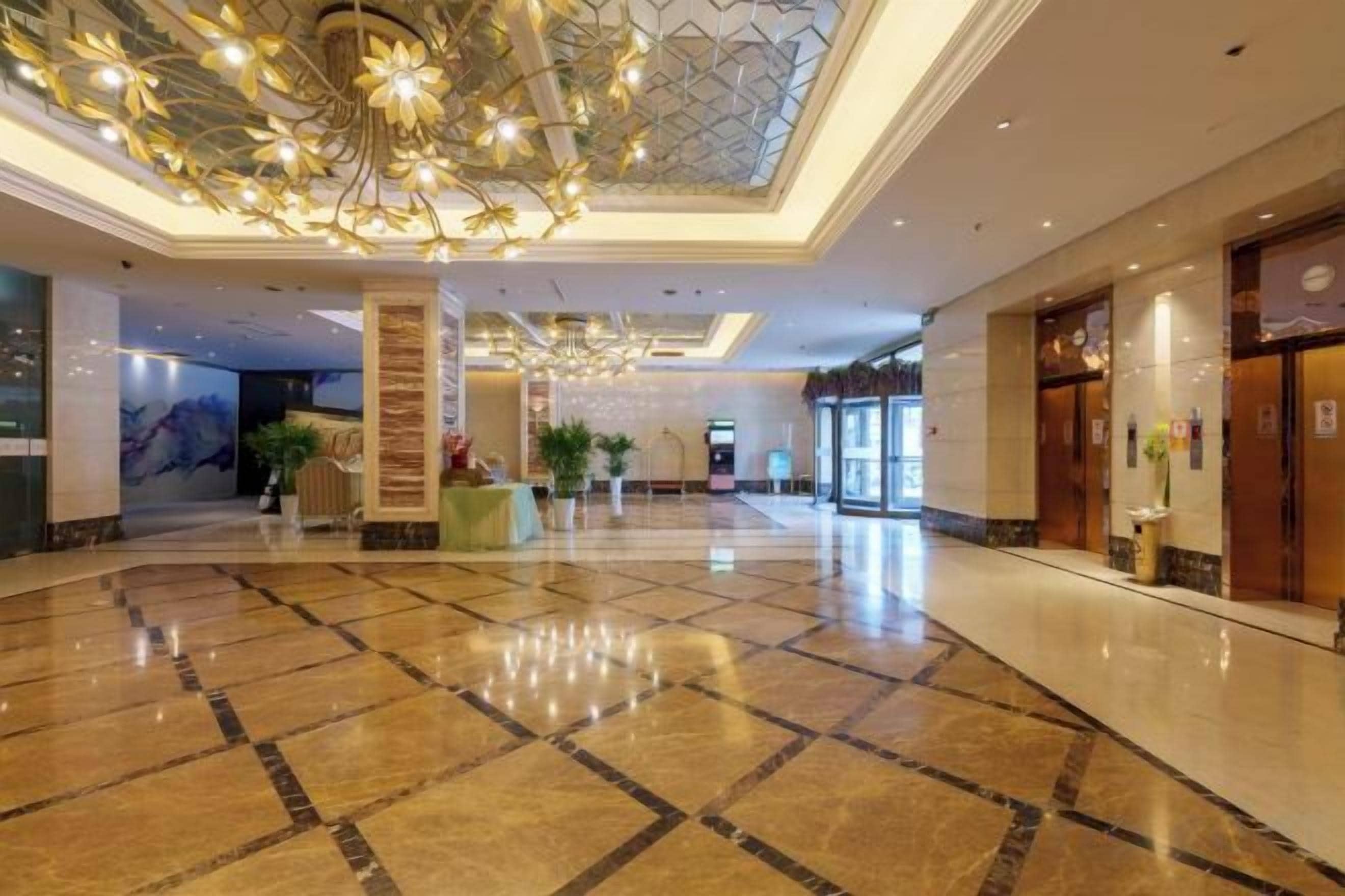A spacious lobby with a polished marble floor, a grand chandelier, and a reception desk.