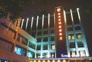A hotel with a prominent vertical sign displaying Chinese characters, multiple floors with illuminated windows, and a visible name "KUNNING GARDEN HOTEL" at the bottom. - Xi'an Kunming Garden Hotel (Seoul South Road Subway Station Branch) (Xi'an)