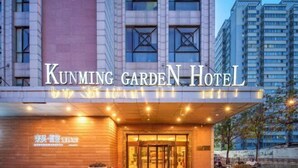 L’extérieur de l’hôtel Kunming Garden, avec son entrée imposante et une enseigne indiquant le nom de l’hôtel.