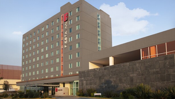 Un hotel moderno con fachada plana, varias ventanas y una entrada destacada con un cartel.