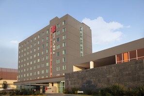 A modern hotel with a flat facade, multiple windows, and a prominent entrance with a sign. - Fiesta Inn Morelia Altozano (Morelia)