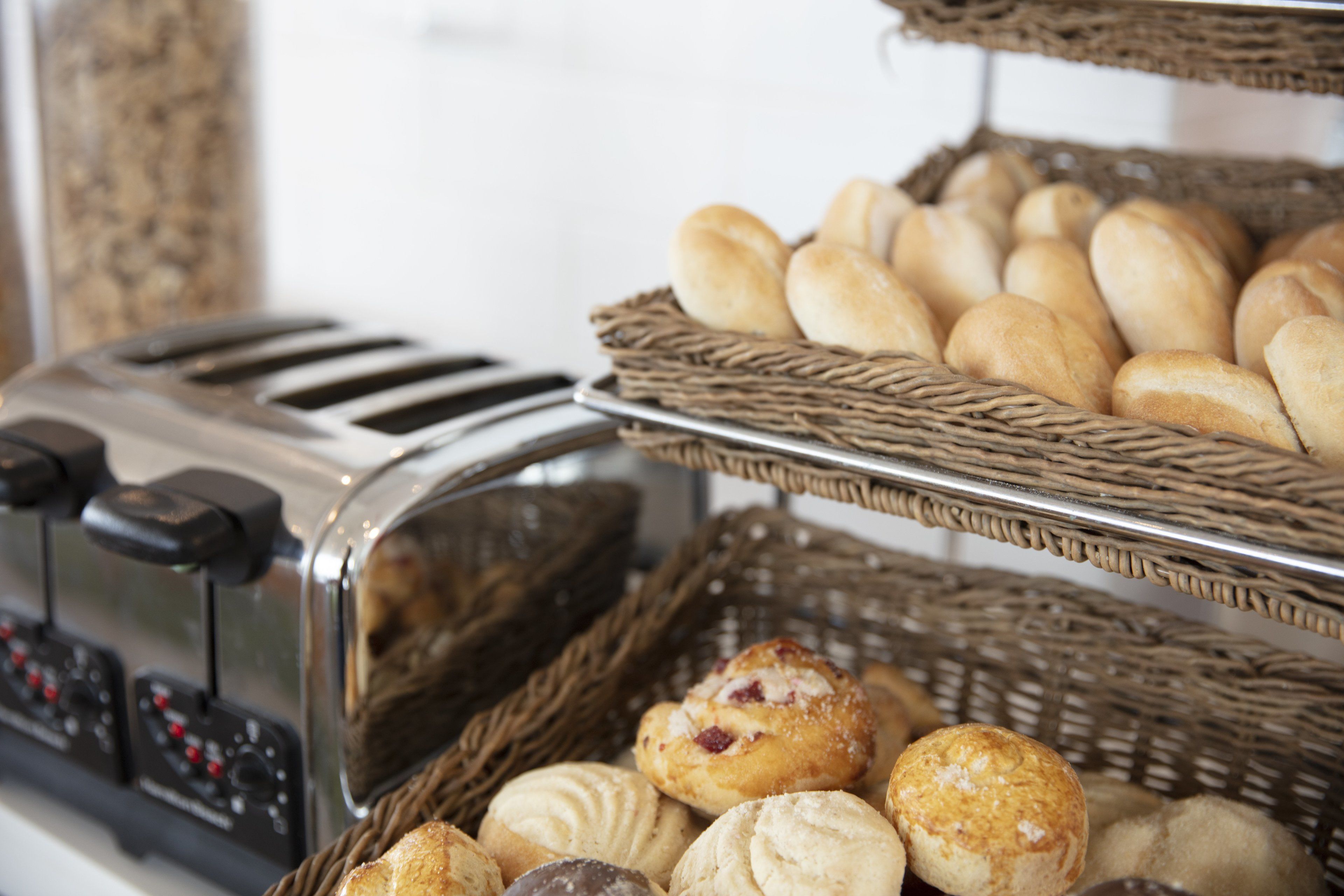 A toaster and two wicker baskets filled with various baked goods.