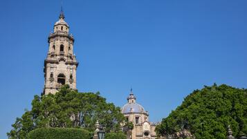 A historic building with a prominent tower and dome, surrounded by lush greenery.