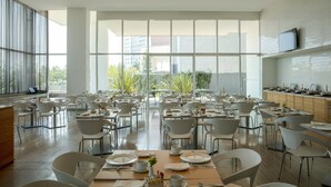 Un comedor espacioso con techos altos y ventanas amplias, que presenta muebles modernos y un diseño limpio y minimalista.