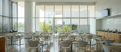 A spacious dining area with high ceilings and large windows, featuring modern furniture and a clean, minimalist design.