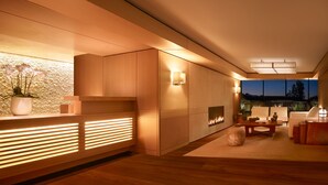 Un interior moderno con un mostrador de recepción de madera, una chimenea y una zona de estar con vistas al exterior.
