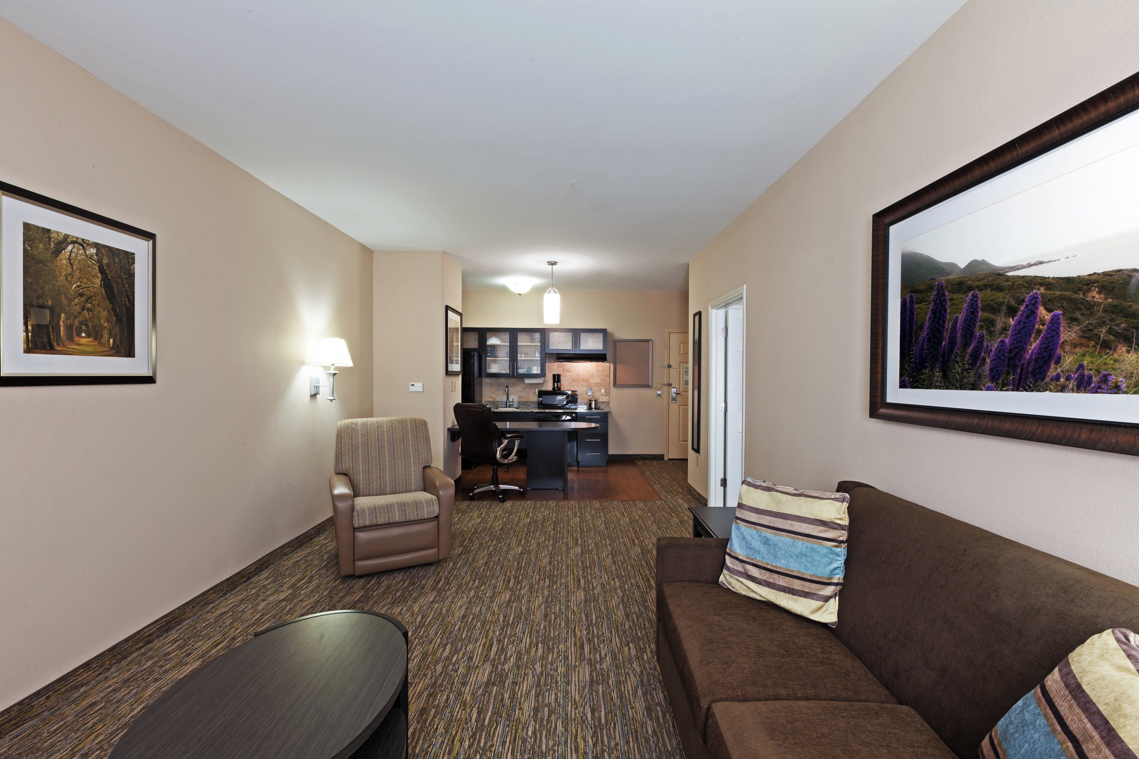 Quarto de hotel com sala de estar, cozinha compacta e vista para o exterior.