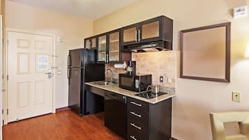 Una cocina compacta equipada con refrigerador, microondas, estufa y alacenas.