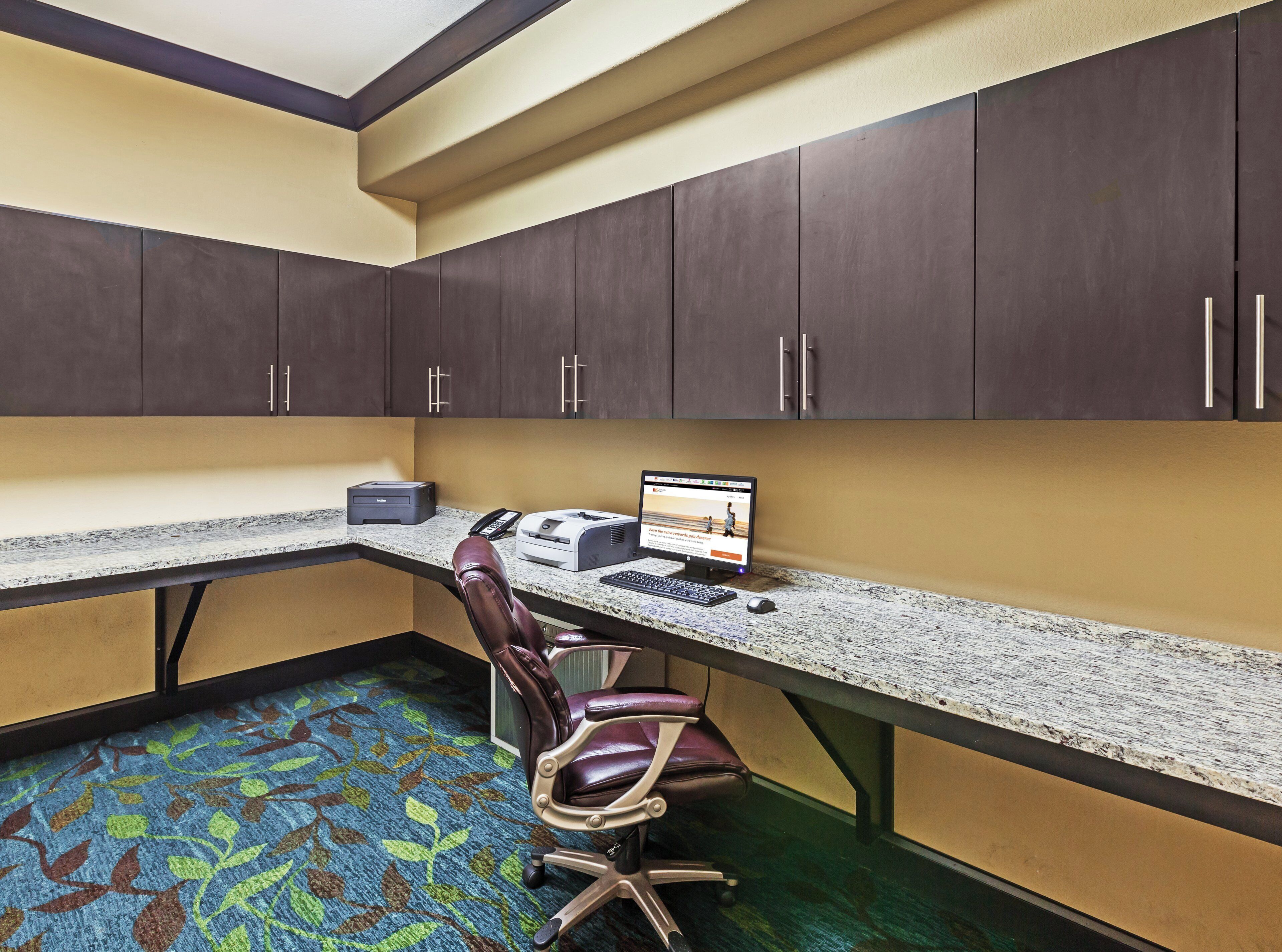 A private office with a desk, computer, printer, and leather chair.