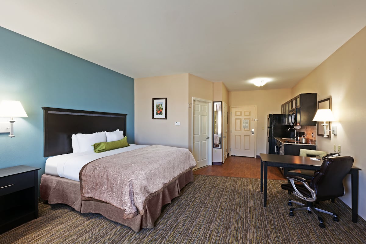 Ein Hotelzimmer mit Bett, Schreibtisch und Küchenzeile.