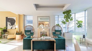 Een moderne hotel lobby met een centrale zithoek, grote ramen en uitzicht over de stad.