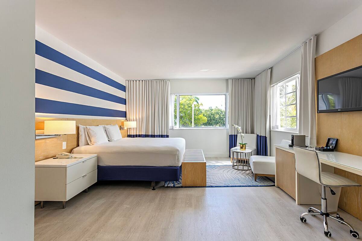 Ein Hotelzimmer mit Bett, Schreibtisch, Stuhl und Fernseher.