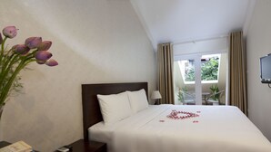 A hotel room with a bed, a nightstand, a lamp, a TV, and a window with curtains. - Rising Dragon Legend Hotel (Hanoi)