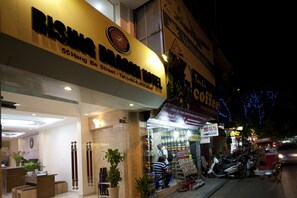 A street view of a building with a sign for 'Rising Bamboo Hotel' and a coffee shop.