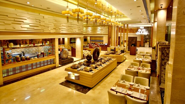 A spacious hotel lobby with a central display of luxury items, multiple seating areas, and a modern chandelier. - Park Ascent (Noida)
