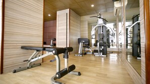 A gym with exercise equipment, wooden walls, and a mirror reflecting the space. - Park Ascent (Noida)