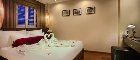 Habitación de hotel con una cama grande, un escritorio con lámpara y tres cuadros en la pared.