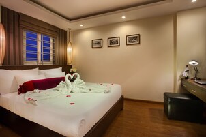 Habitación de hotel con una cama grande, un escritorio con lámpara y tres cuadros en la pared.