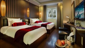 A hotel room with two beds, a desk with a computer, a TV, and a window with a view of buildings. - Golden Art Hotel (Hanoi)