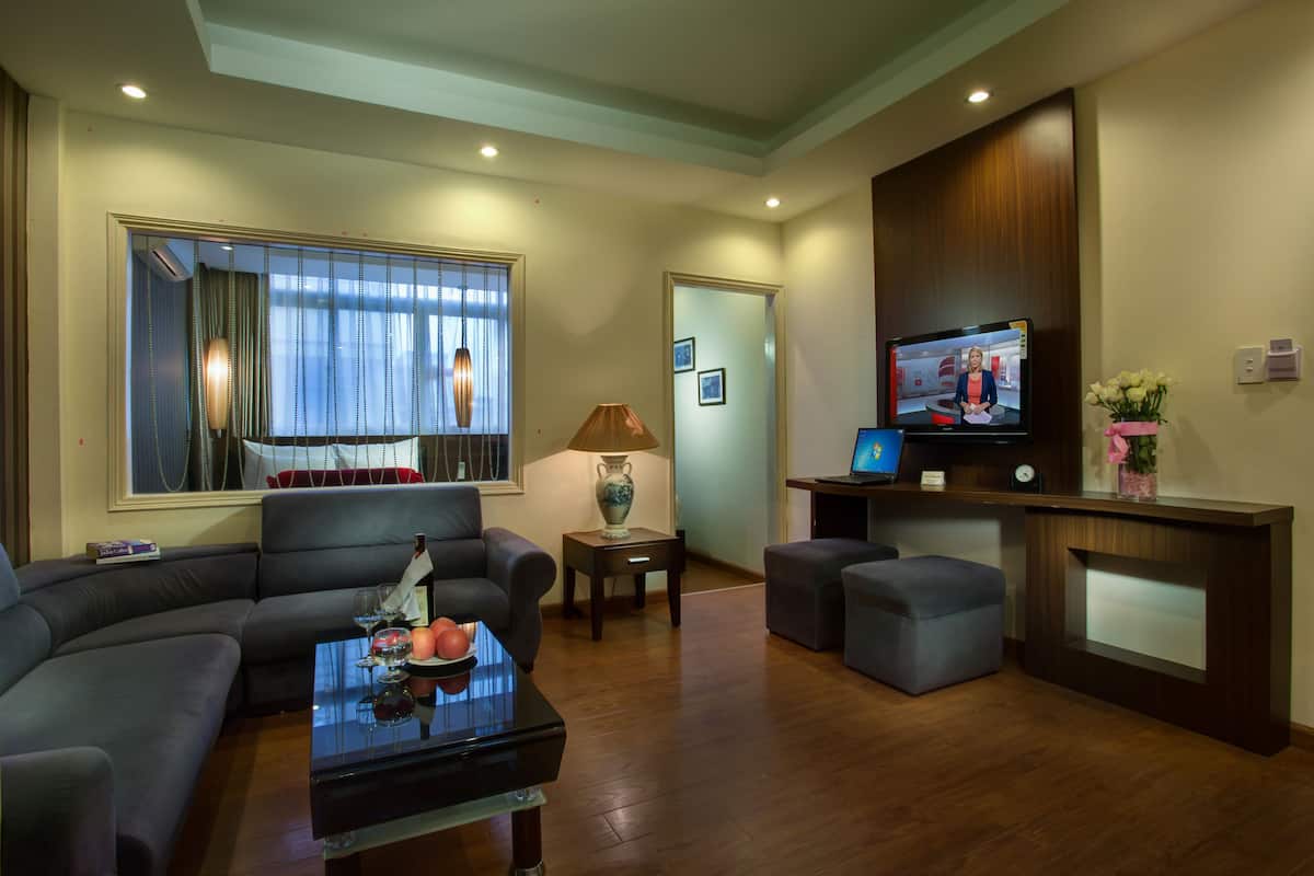 A modern living room with a sofa, ottoman, coffee table, and a television.