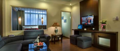 Una sala de estar moderna con un sofá, un reposapiés, una mesa de centro y un televisor.
