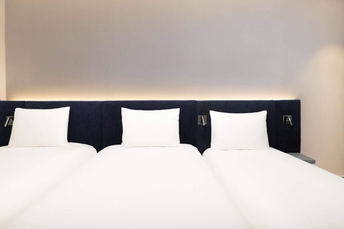 Ein Hotelzimmer mit einem großen Bett, zwei Nachttischen und einem Kopfteil mit integrierter Beleuchtung.