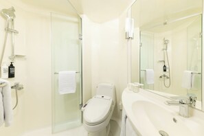 Une salle de bain moderne dotée d’une douche à parois de verre, de toilettes et d’un lavabo avec un grand miroir.