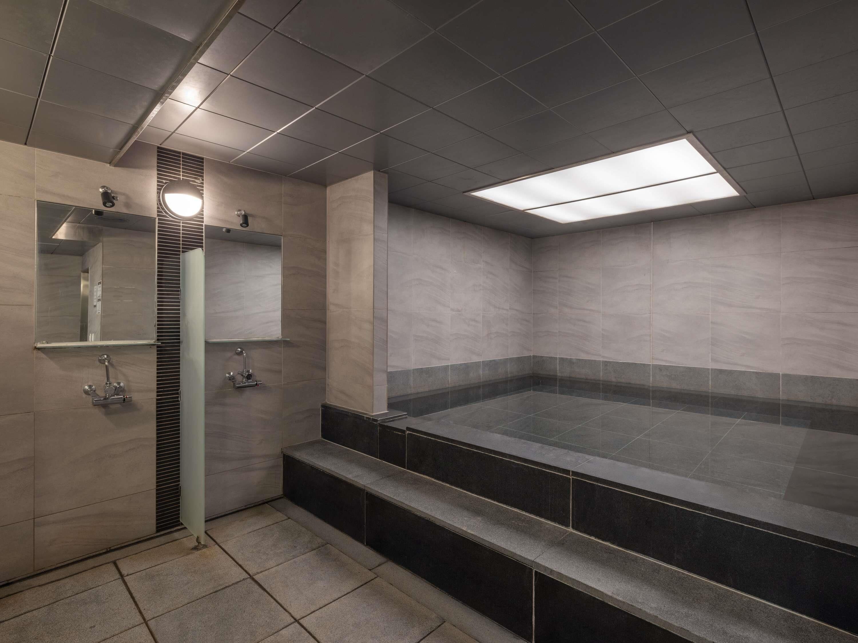 A modern bathroom with a large bathtub, a shower area, and a mirror.