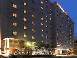 Un hotel de varios pisos con ventanas iluminadas y un cartel llamativo.