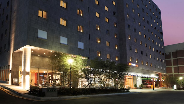 Een meerlaags hotel met een modern ontwerp, met een opvallend 'Ibis'-bord aan de bovenkant.