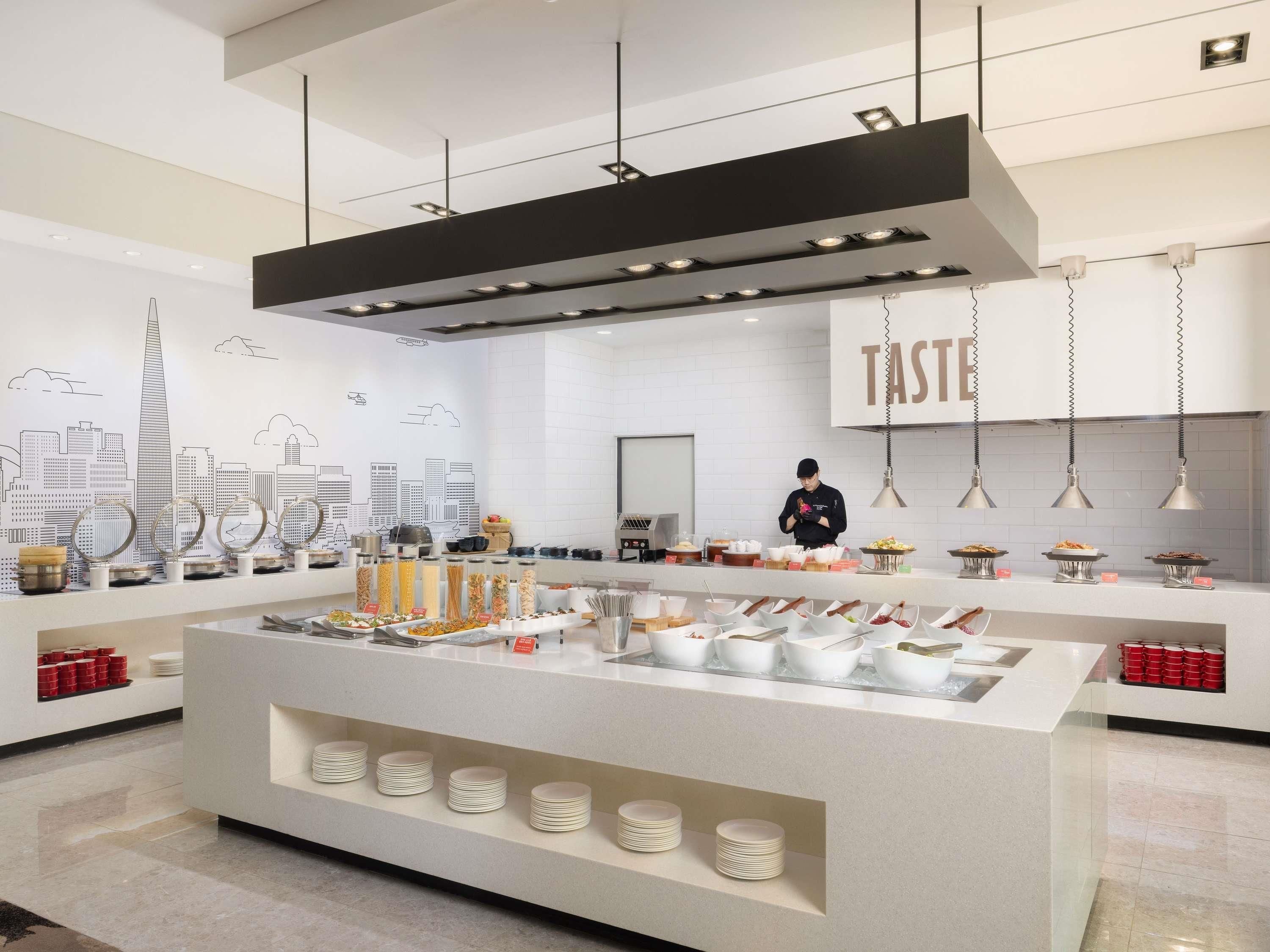 A modern kitchen with a central island, various food items, and a cityscape mural on the wall.