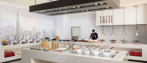 A modern kitchen with a central island, various food items, and a cityscape mural on the wall.