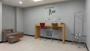 Een moderne kamer met een bank, een bureau, twee barkrukken, een karretje en een muur met een motiverende quote.