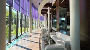 A modern interior with large windows, a pool, and seating areas. - Hotel Novotel Banjarmasin Airport (Banjarbaru)