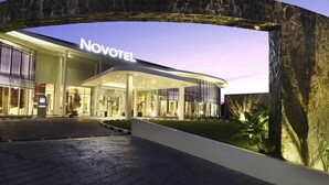 A modern hotel entrance with a curved stone archway and the name 'NOVOTEL' prominently displayed. - Hotel Novotel Banjarmasin Airport (Banjarbaru)